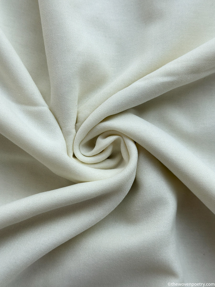 Close-up of ivory white fabric with a swirl pattern by Woven Poetry