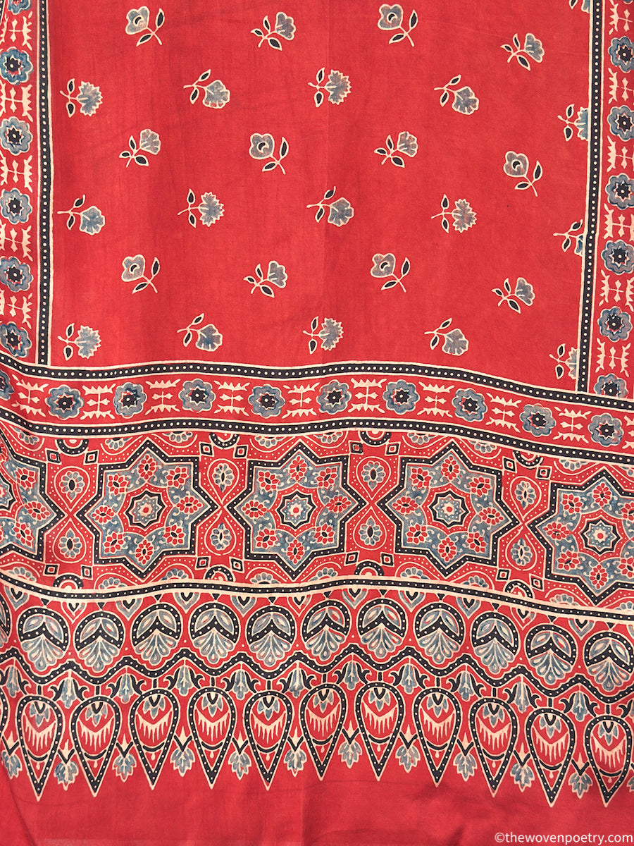 Close-up of handcrafted red stole featuring Ajrakh inspired floral motifs and intricate border design
