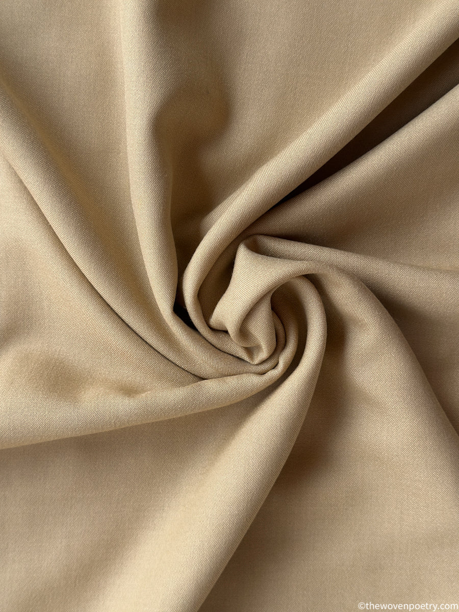 Close-up of beige fabric with a swirl pattern by Woven Poetry