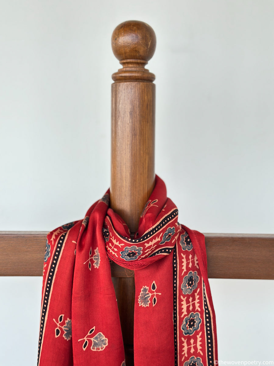 Full view of red handcrafted stole with floral Ajrakh inspired motifs and decorative border patterns